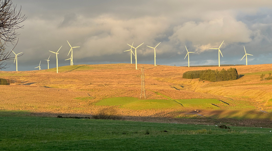 Wind turbines turning gently on a golden Scottish hillside at sunset, Solway Blankets Head Quarters – a symbol of renewable energy and sustainable living in rural Scotland