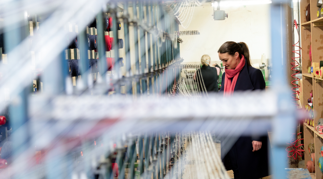 Victoria exploring a traditional British weaving mill, surrounded by rows of yarn – celebrating the people and processes behind Solway Blankets.