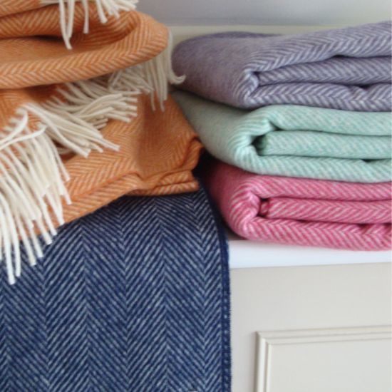 Stack of Solway Blankets in various colours, orange, blue, purple, green and pink