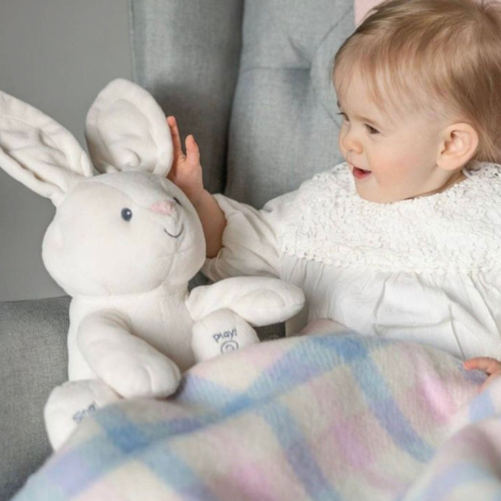 Smiling baby cuddled up with a soft pastel check wool blanket and plush bunny – part of the Baby and Children's Blanket Collection.