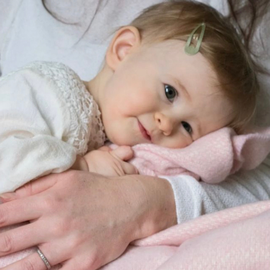 Baby girl snuggled in a soft pink blanket, resting in her mother’s arms – part of the Baby Girl Blanket Collection.