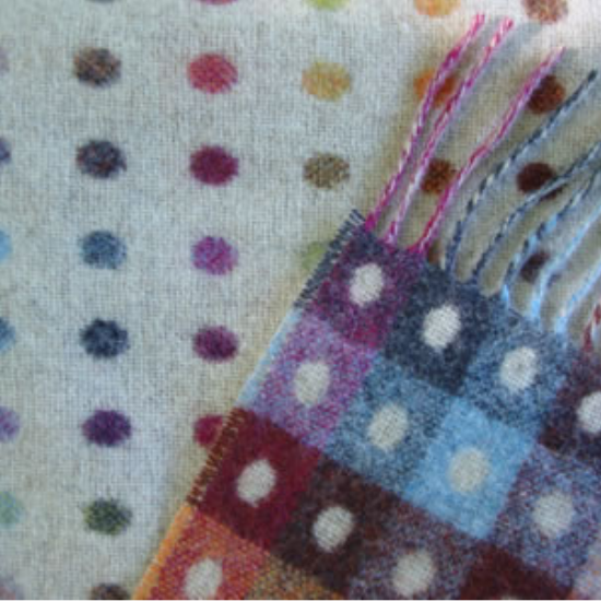 Soft wool throw featuring multicoloured spot and square patterns in rainbow tones—part of the "By Design" Blanket and Throw Collection celebrating playful, modern motifs.
