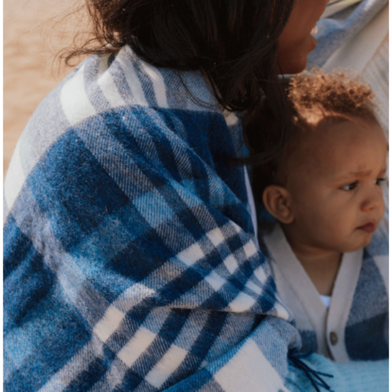 Mother and child wrapped in a cosy blue and white checked wool blanket, enjoying a tender moment outdoors – the perfect thoughtful gift for families from Solway Blankets.
