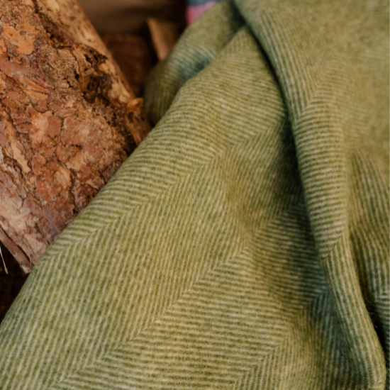 Close-up of a green herringbone wool throw from the Green and Teal Blanket Collection – soft, sustainable, and inspired by the natural tones of the British countryside.
