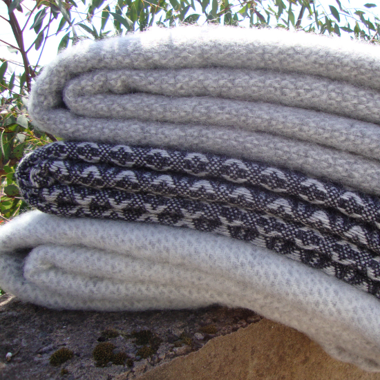 Stack of grey wool blankets and throws in soft tones and textured weaves – a calming, versatile collection perfect for neutral and minimalist interiors.