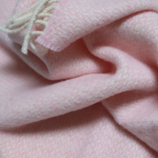 Close-up of a luxuriously soft pale pink cashmere baby blanket with delicate fringe, perfect for gifting or keeping little ones cosy in style.