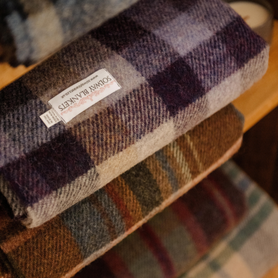 Traditional plaid and check blankets folded and stacked in an old whisky cask