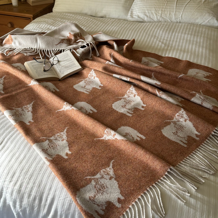 Example of a Scottish woven jacquard blanket featuring a special design of Highland Cows, in a guest house, hotel, hospitality setting