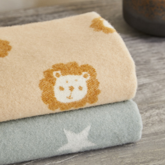 Two folded unisex baby blankets – one in warm beige with lion faces and the other in gentle green with white stars – from the Neutral Baby Blanket Collection.