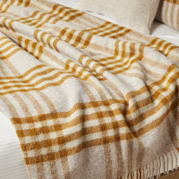 Extra large blanket with mustard and oatmeal checked pattern draped over a bed.