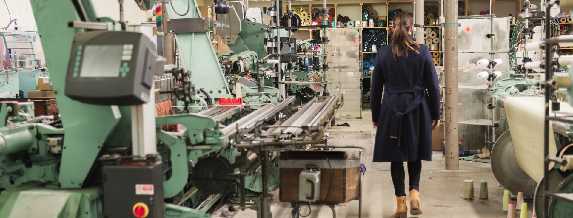 Person walking through a traditional blanket weaving mill with machinery on either side