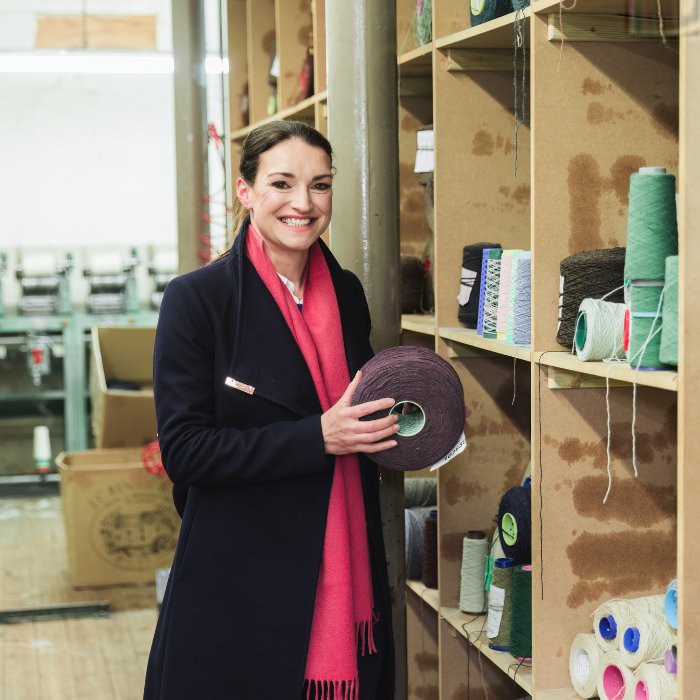 Victoria Lane founder of Solway Blankets holding a cone of yarn in a traditional Scottish Weaving Mill