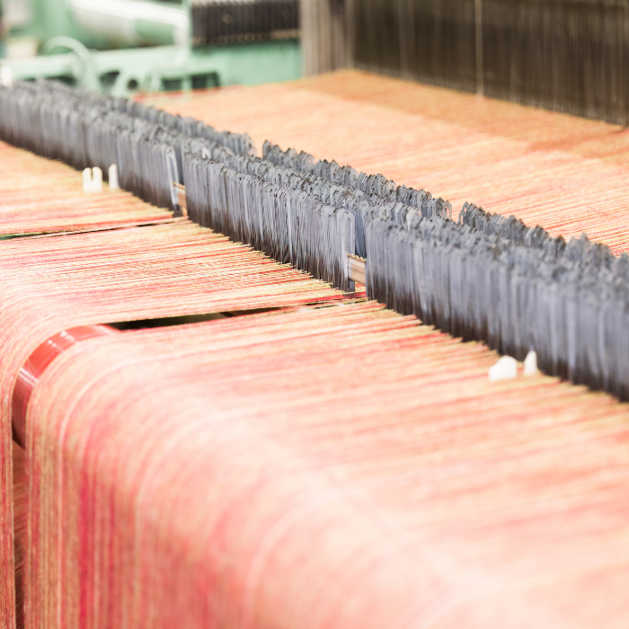Traditional blanket textile production with yarn and metal needles on a loom.