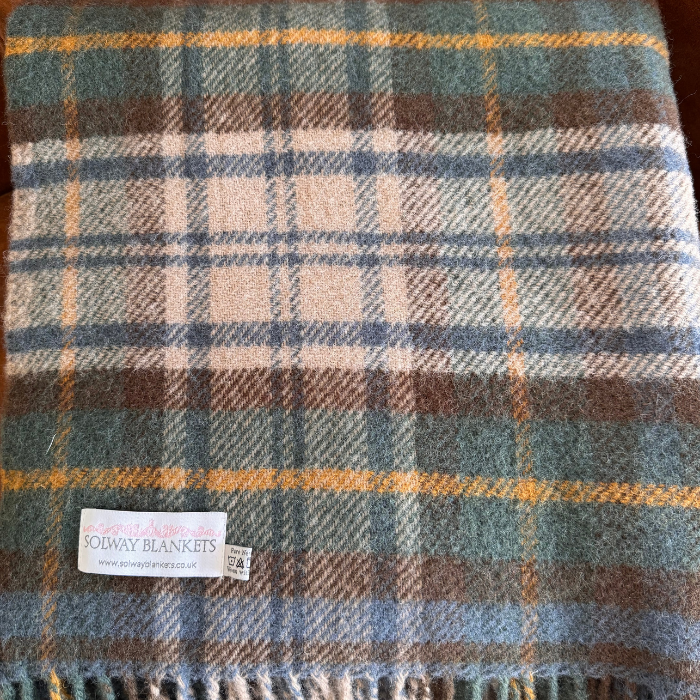 A close-up shot of the Antique Dress Gordon Tartan pure wool blanket, folded up and showing Solway Blankets brand label