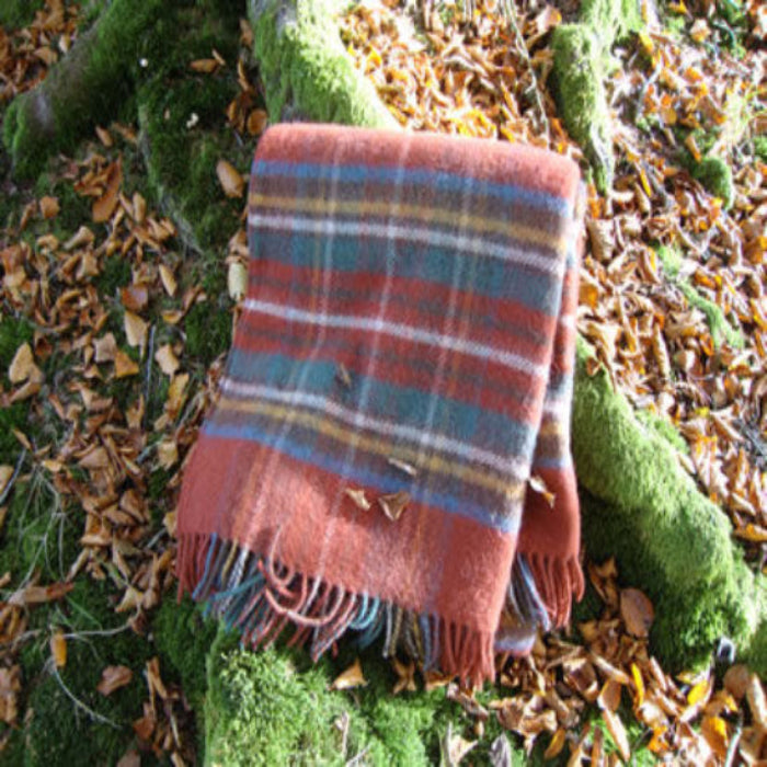 Antique Royal Stewart Tartan Plaid blanket on a bed of autumn leaves and moss