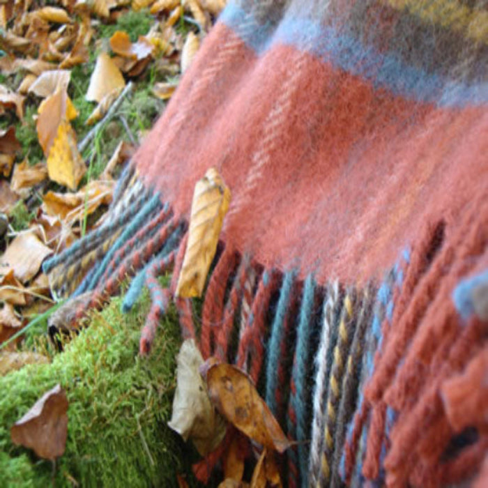 Close up of Antique Royal Stewart Tartan Plaid wool blanket on a bed of autumn leaves