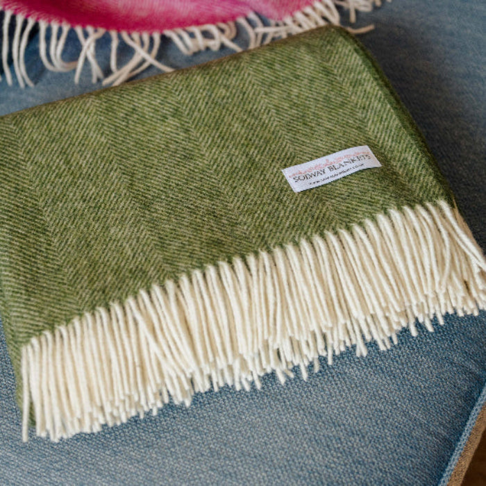 Apple Green Herringbone Shetland Wool Blanket Throw with white fringe on a blue couch