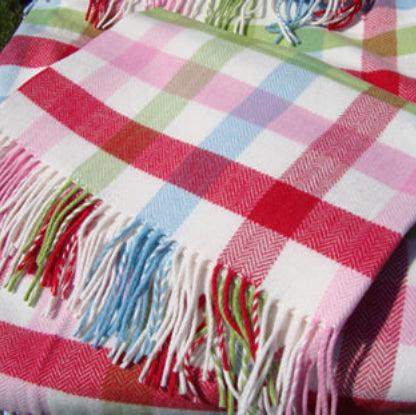 A close-up of the bold Baby Bunting Cashmere Mix check blanket with multicoloured fringe, featuring a check pattern of pink, red, light blue, and green checks on a white base.