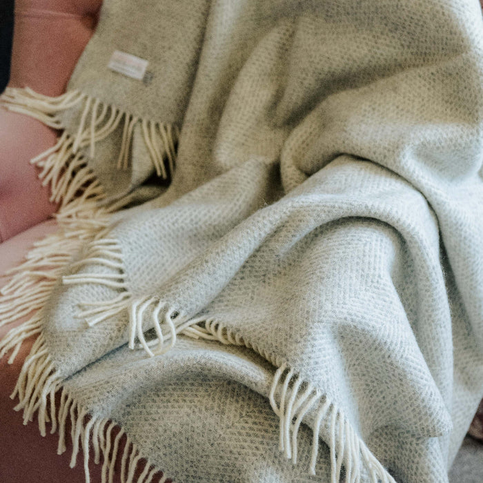 Grey silver textured wool blanket with fringes draped over a pink chair