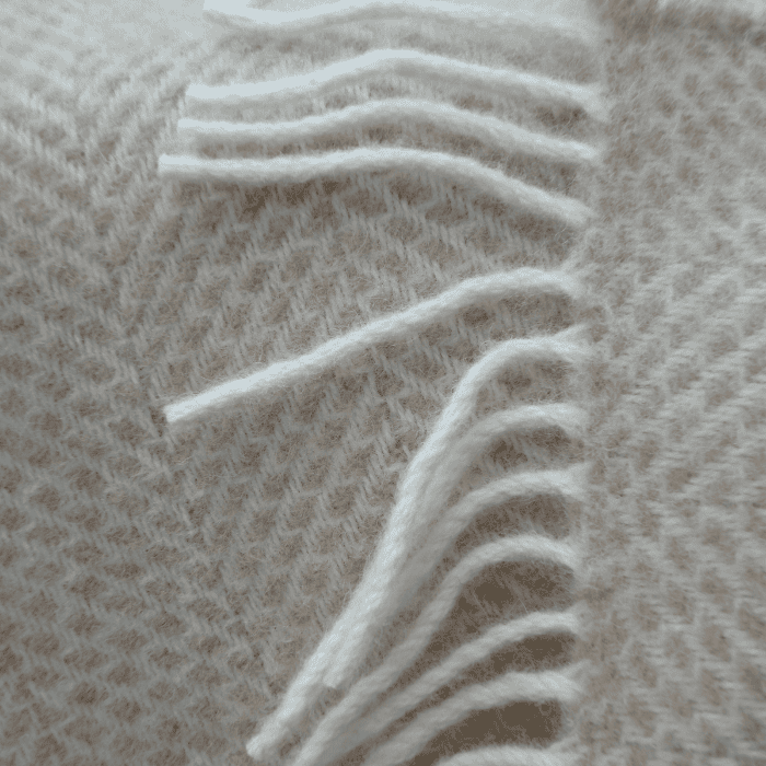 Close-up of beehive beige throw blanket fringe, showcasing soft texture and white fringe