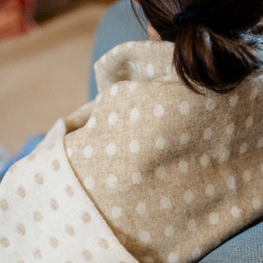 Close up of a person with a beige and cream spotted blanket wrapped around them