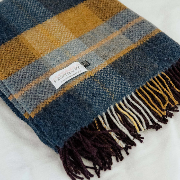 Folded plaid throw with fringes on a white background