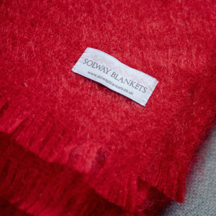Berry Red Mohair Throw blanket with a 'Solway Blankets' label on a settee