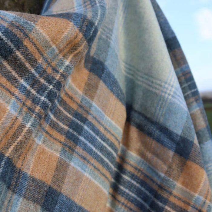 Close-up of plaid Blue Kintyre Check Shetland Wool Throw with blue and brown colours, blurred background