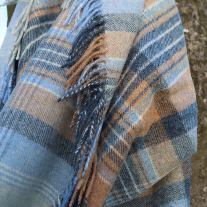 Blue Kintyre Check Shetland Wool Throw Blanket draped over a tree with a natural background