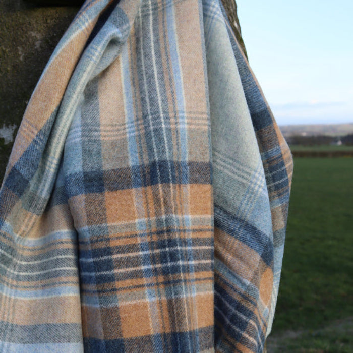 Blue Kintyre Check Shetland Wool Throw Blanket with blue, brown and beige colours on a textured surface.