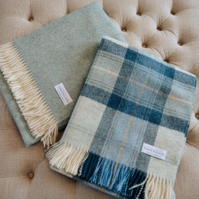 Blue Skye Check Shetland Wool Blanket plaid and Duck Egg Herringbone blanket on a beige cushioned surface
