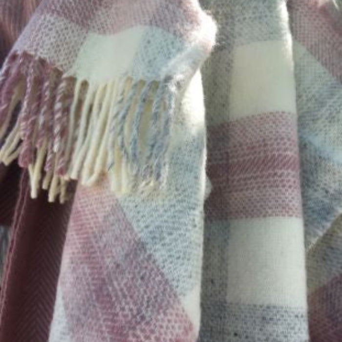 Plaid wool blanket with fringes in pink, cream, and grey colours.