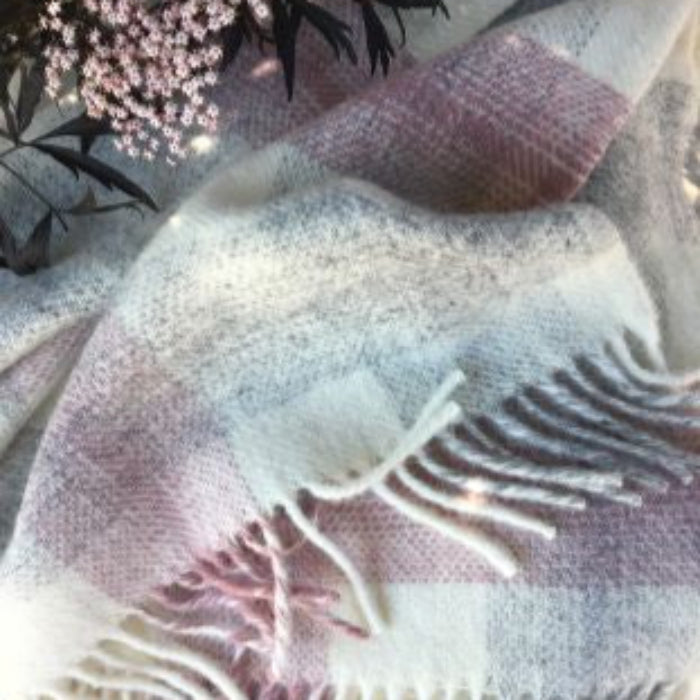 Textured pink, cream and grey check wool blanket with fringes on a neutral background