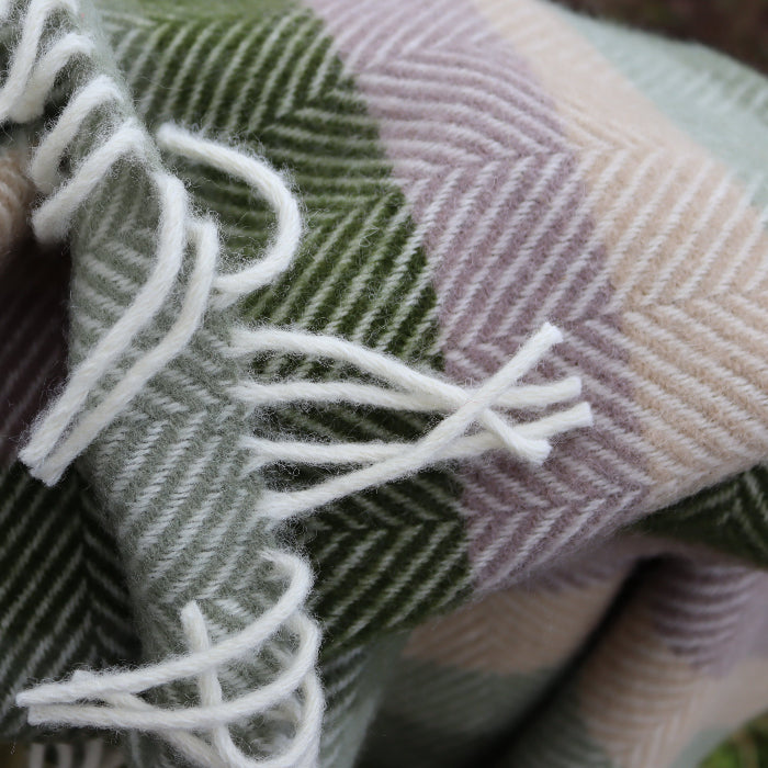 Close up of a plaid green woollen fabric with white fringe strands on a checkered pattern