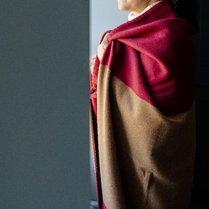 Close up of a person with a burgundy red and tan cashmere blanket throw wrapped around them