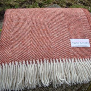 Brick Rust toned Herringbone woven Wool Blanket with white fringe on a natural surface