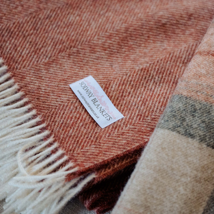 Brick, burnt orange coloured Herringbone Shetland Wool Blanket with a visible Solway Blankets brand tag