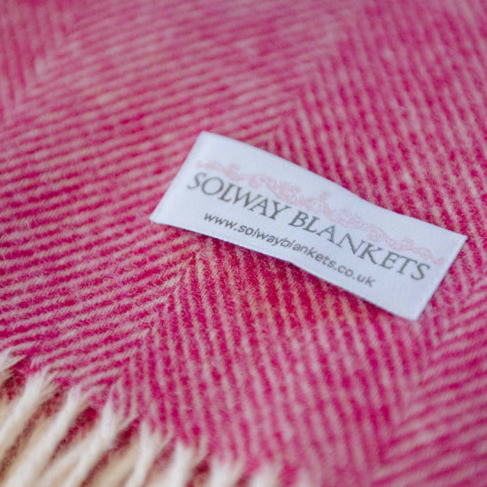 Close-up of Bright Pink Herringbone Shetland Wool Blanket with a Solway Blankets label.