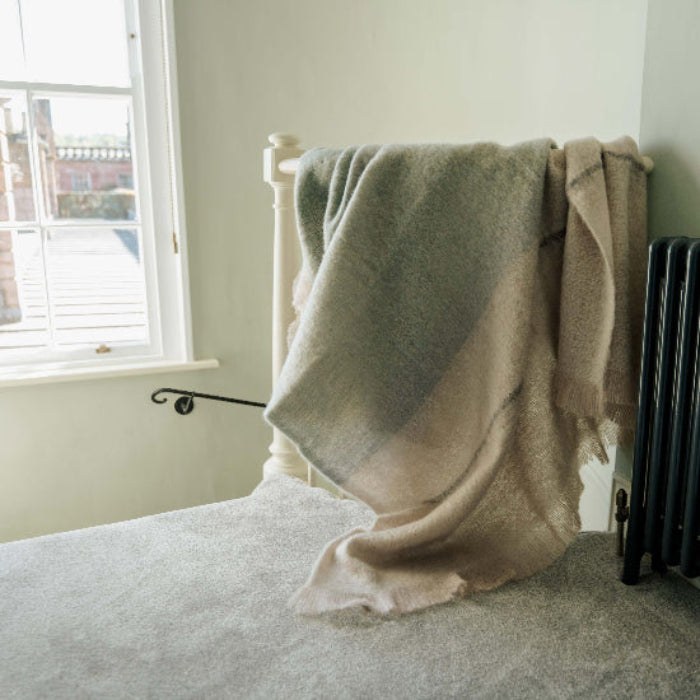 Celadon Mohair Throw in muted green with grey and jade undertones, draped over a staircase next to a window in a room overlooking a Scottish Castle