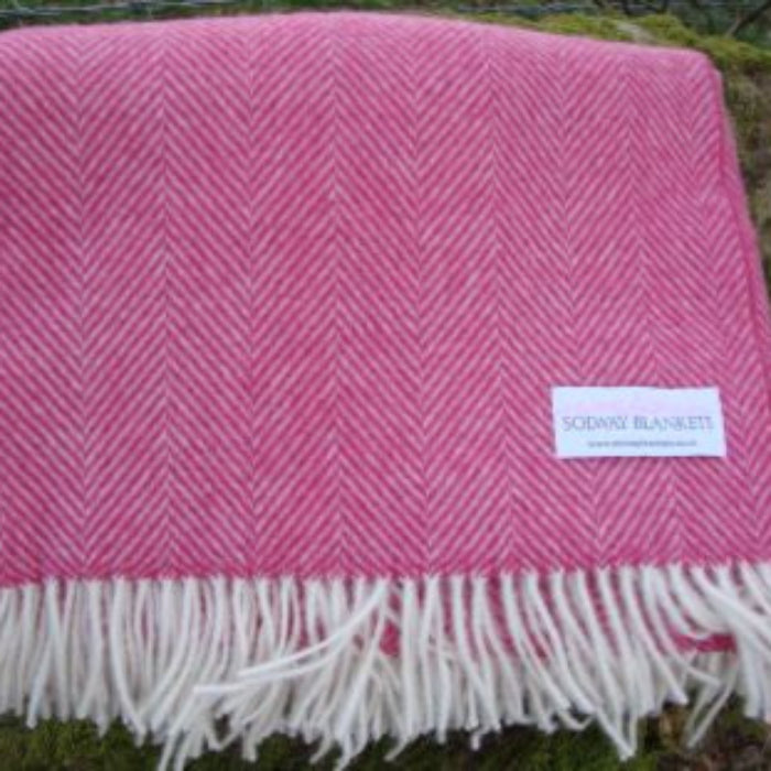 Pink herringbone patterned blanket with white fringe and a visible Solway Blankets label in a outdoors setting