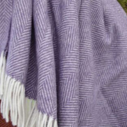 Purple herringbone blanket with white fringe on a natural background