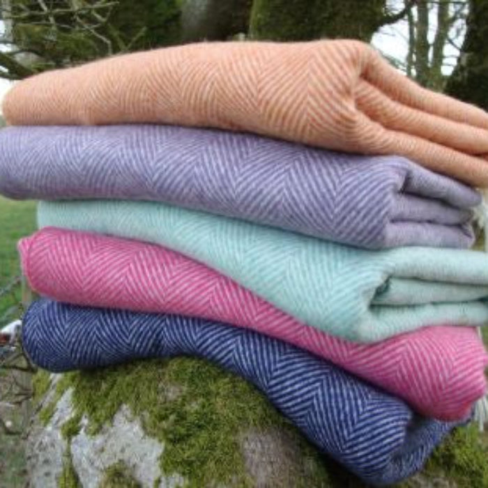Stack of folded colorful herringbone patterned wool blankets on a tree stump outdoors