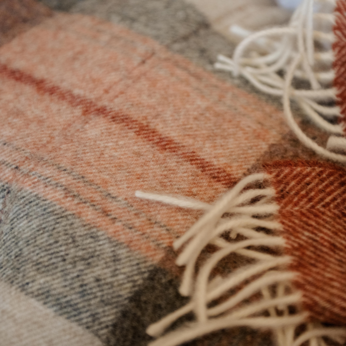 Coral Skye Check Shetland Wool Throw Plaid blanket with fringes on a soft focus background