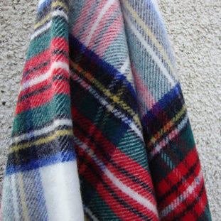 Dress Royal Stewart Tartan Plaid Pure Wool Blanket with red, blue, green and yellow colours on a textured surface.