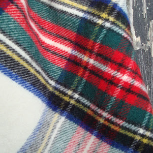 Close-up of a dress royal stewart tartan blanket with red, green and blue colors on a textured background.