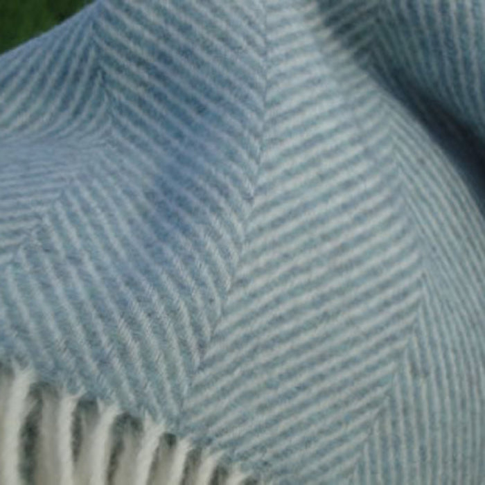 Close-up of the Duck Egg Blue Herringbone Shetland Wool Throw a blue and white herringbone patterned fabric with a fringe.