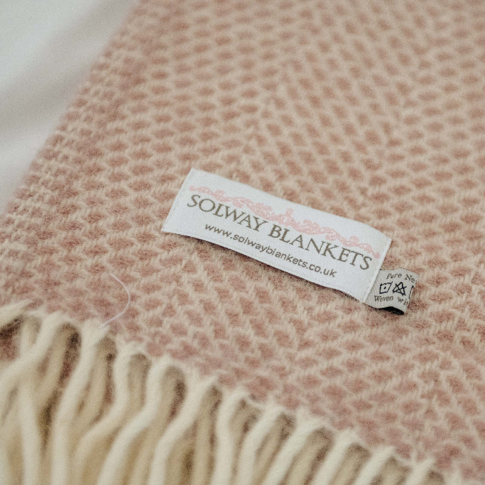Close up of a Solway Blankets label on a woven dusky pink blanket with fringes.