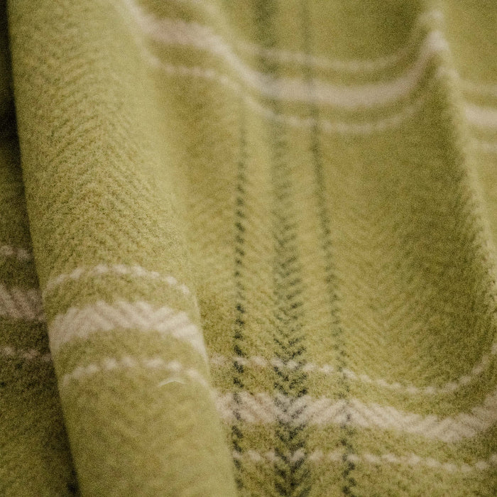 Close up of an emerald green plaid throw with a white stripe