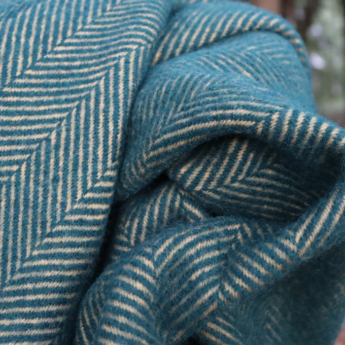 Close up of a emerald and mustard wool blanket with a herringbone pattern