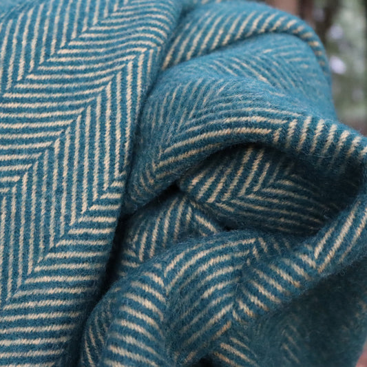 Close up of a emerald and mustard wool blanket with a herringbone pattern